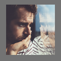 photo of a depressed man looking out a window. Learn more about the symptoms of depression from an online therapist in California at the relationship therapy center